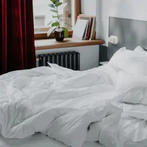 habiacion con cama con ropa blanca desteñida